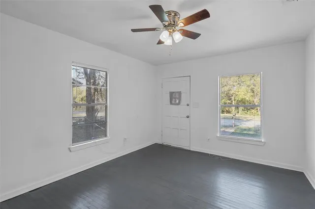 a view of an empty room with a window and wooden floor