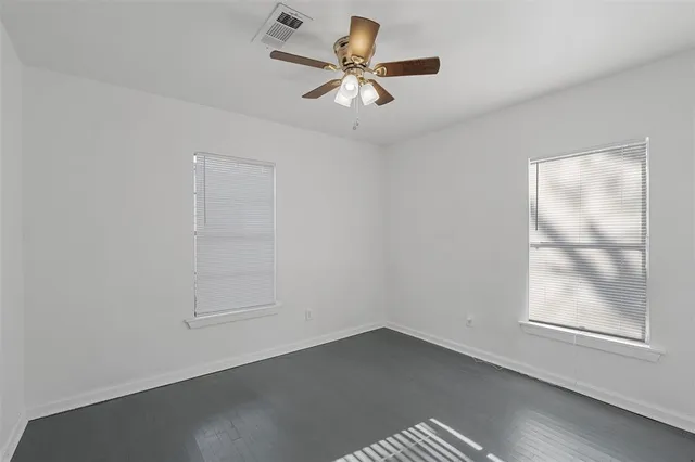 an empty room with a window and a ceiling fan