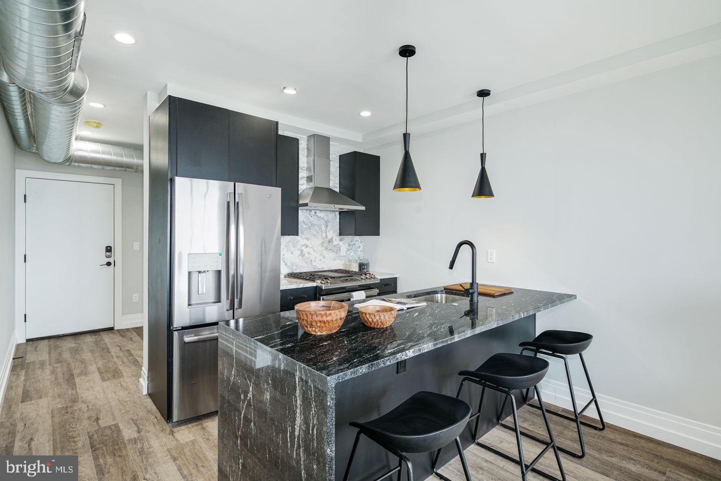 a kitchen with stainless steel appliances granite countertop a stove a refrigerator and a wooden floor