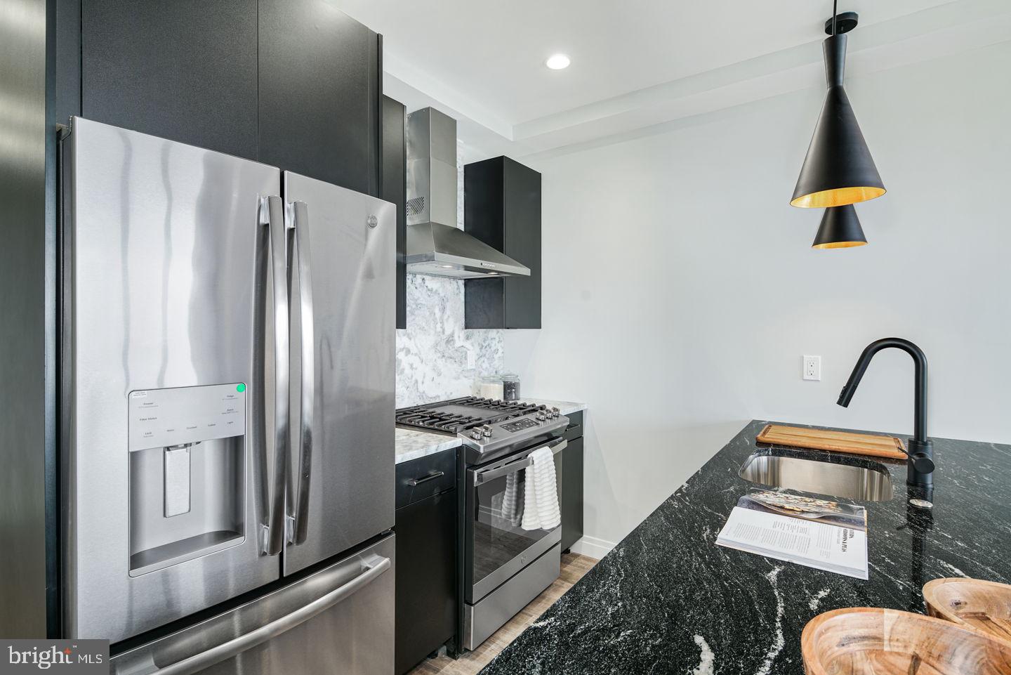 526 Brown Street, Unit 207 Philadelphia, PA 19123 - Photo 7 of 27 a kitchen with stainless steel appliances granite countertop a refrigerator a stove and a sink with wooden floor