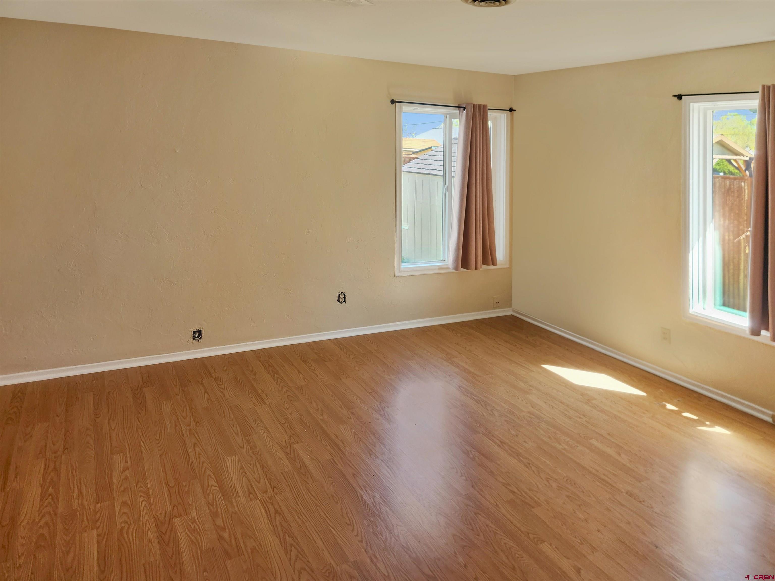 206 North Washington Street Cortez, CO 81321 - Photo 12 of 19 an empty room with wooden floor and windows