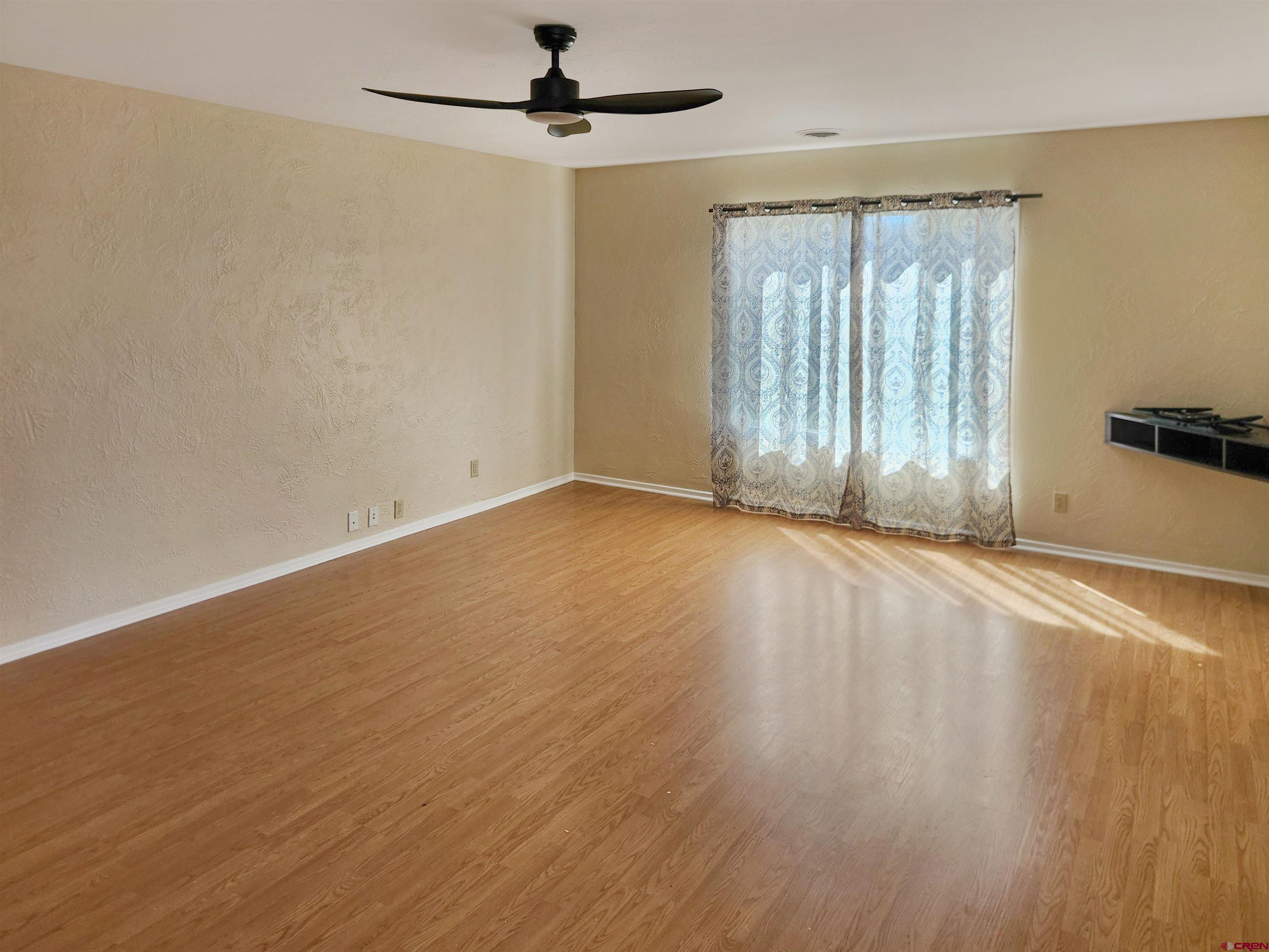 206 North Washington Street Cortez, CO 81321 - Photo 4 of 19 an empty room with wooden floor fan and windows