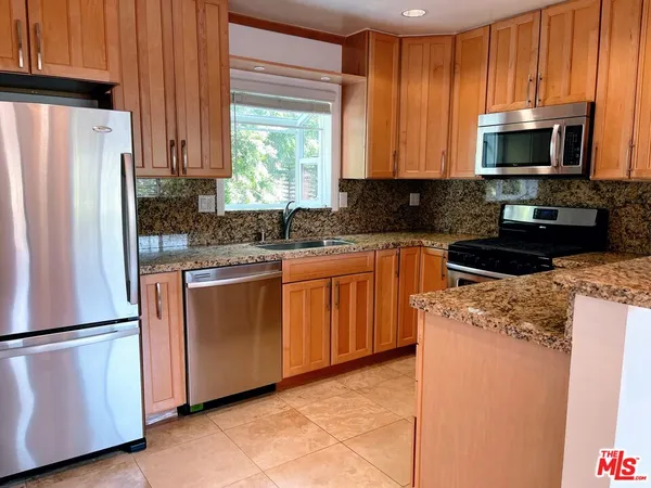 a kitchen with stainless steel appliances granite countertop a refrigerator stove a sink and dishwasher with wooden floor