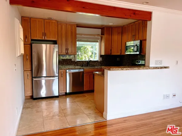 a kitchen with stainless steel appliances granite countertop a refrigerator a stove a sink and dishwasher with wooden floor