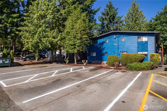 a view of a house with a yard plants and large tree