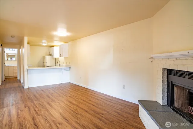 a view of kitchen and empty room with wooden floor