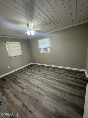 a view of an empty room with window and wooden floor