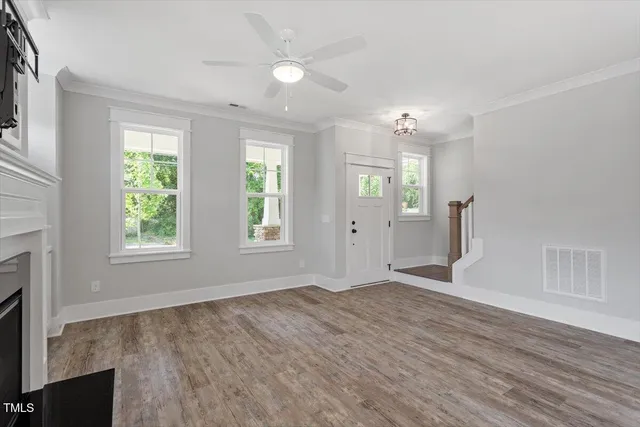 a view of an empty room with window and wooden floor