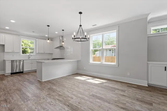 a open kitchen with kitchen island white cabinets and a chandelier