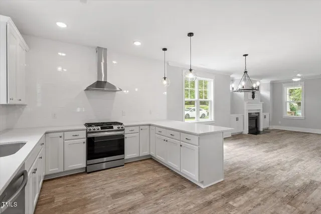 a large kitchen with stainless steel appliances granite countertop a stove a sink a oven and a wooden floors