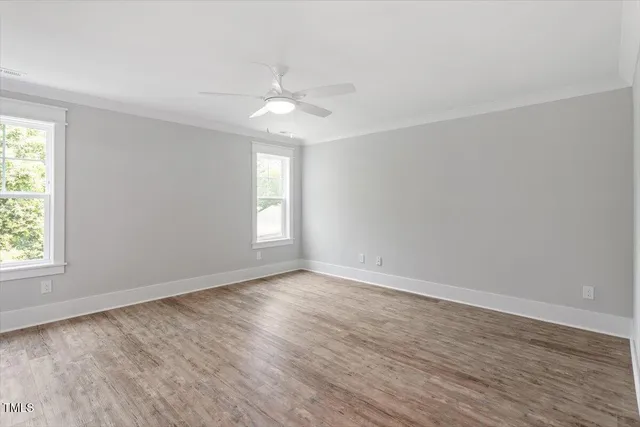 an empty room with wooden floor fan and windows
