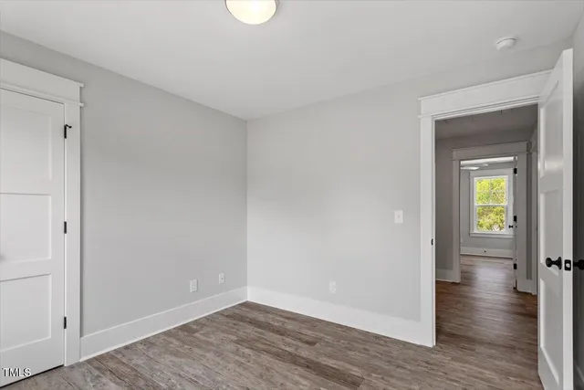 a view of an empty room with wooden floor and closet
