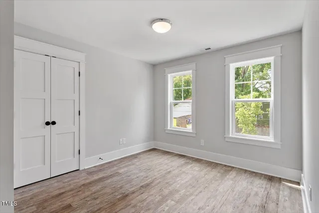 a view of an empty room with wooden floor and a window