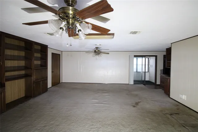 an empty room with windows and fan