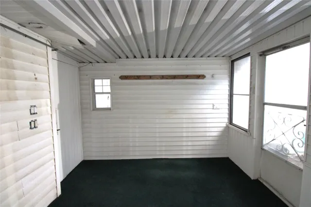 a view of a hallway with a white wooden floor and a window
