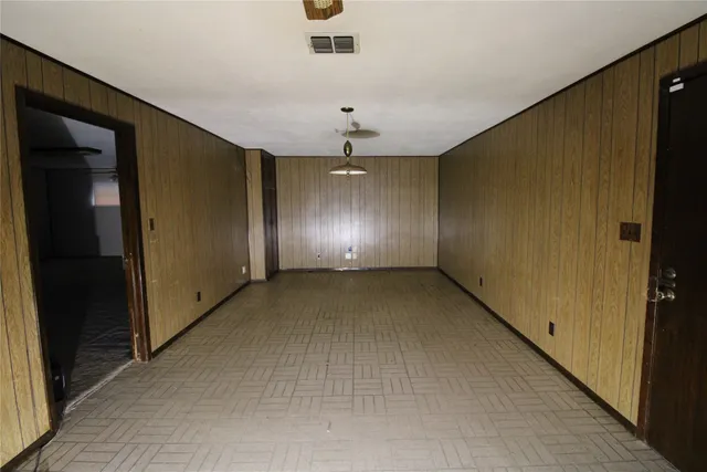 an empty room with chandelier fan and windows