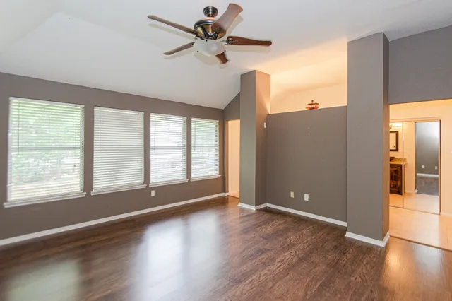 a view of an empty room with window and wooden floor