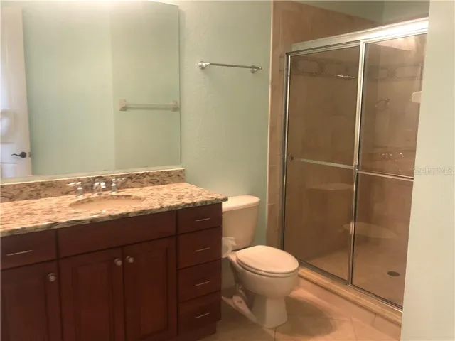 a bathroom with a granite countertop sink toilet and shower