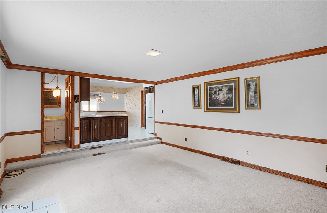 5611 Ralston Drive Parma, OH 44129 - Photo 14 of 39 Unfurnished living room with light colored carpet, ornamental molding, and a chandelier