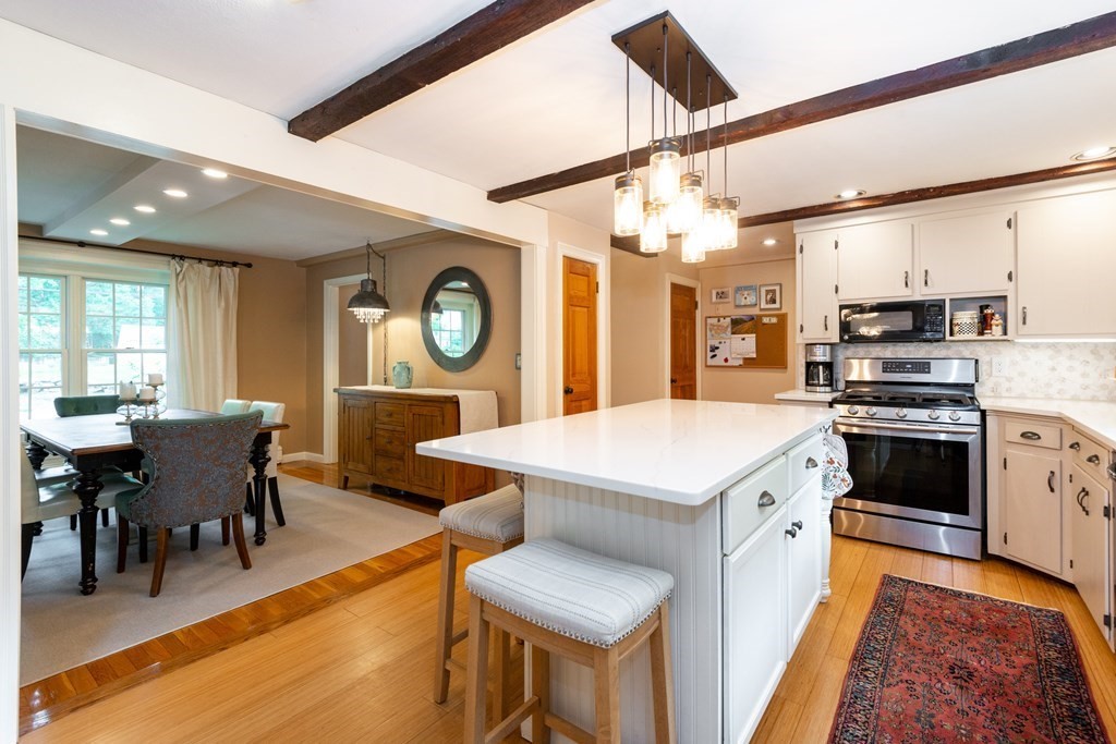 9 Parish Road Georgetown, MA 01833 - Photo 14 of 42 a kitchen with stainless steel appliances granite countertop a stove a sink dishwasher and a dining table with wooden floor