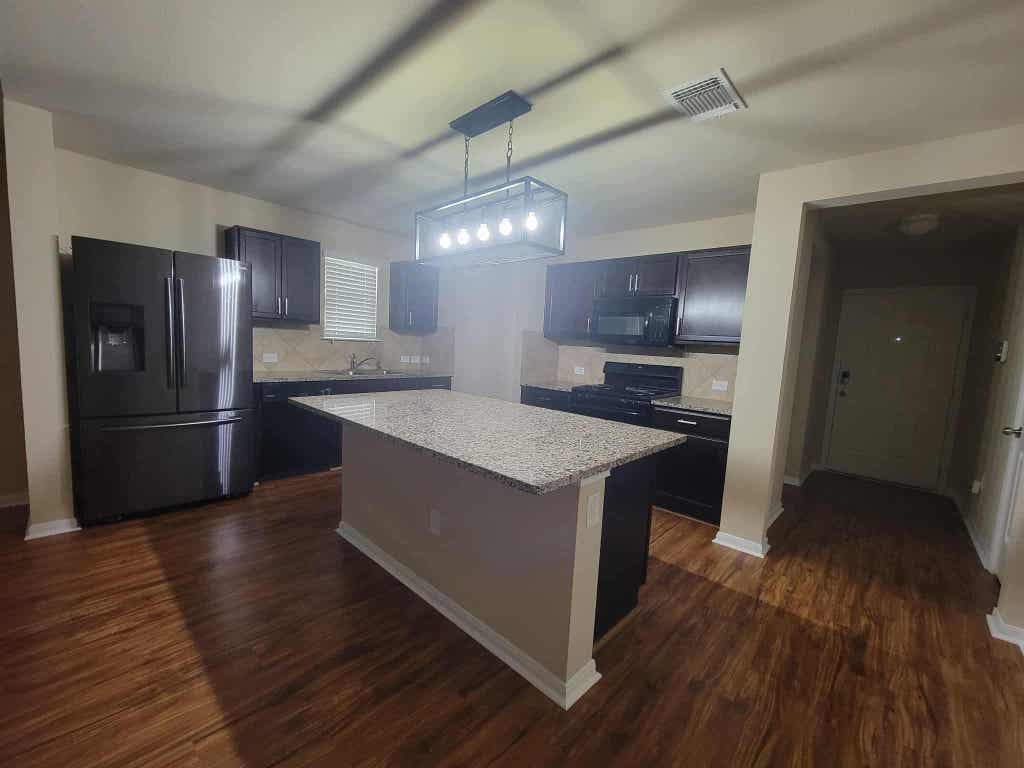 213 Camellia Drive Hutto, TX 78634 - Photo 12 of 27 a kitchen with granite countertop a refrigerator a stove top oven and wooden floor