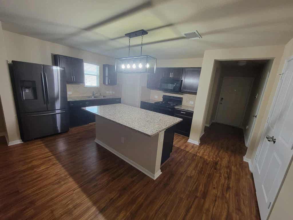 213 Camellia Drive Hutto, TX 78634 - Photo 9 of 27 a kitchen with stainless steel appliances granite countertop a refrigerator a sink dishwasher a stove and white countertops with wooden floor