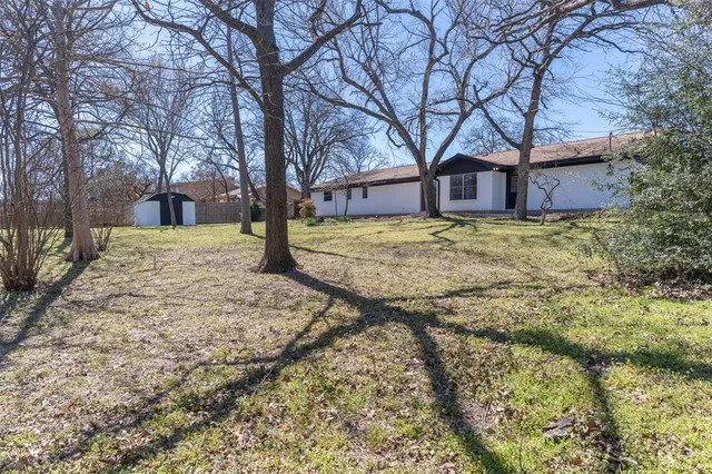 a large tree in front of a brick house with large trees