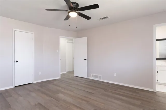 an empty room with wooden floor and ceiling fan