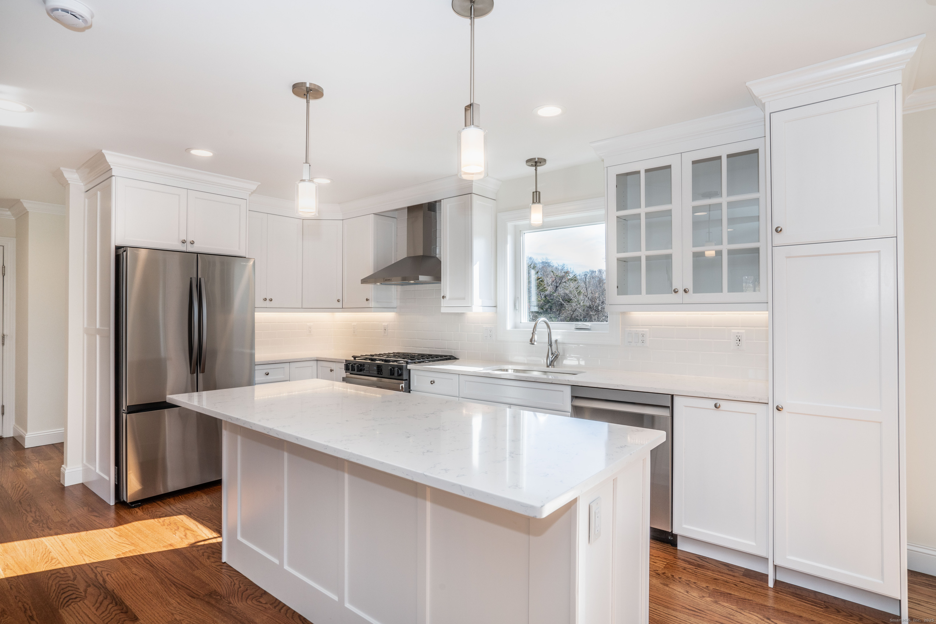 a kitchen with stainless steel appliances granite countertop a sink a refrigerator and a stove with wooden floor