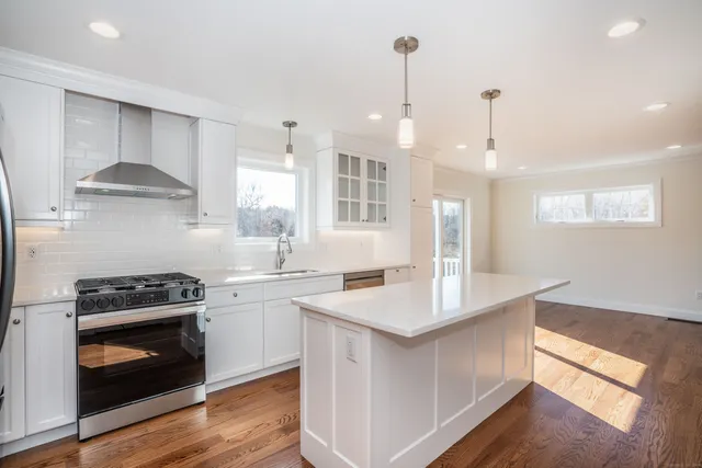 a kitchen with a stove a sink and a wooden floors