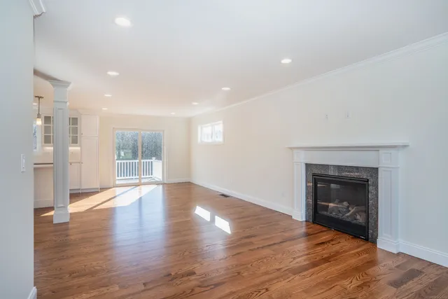 a view of an empty room with wooden floor fireplace and a window