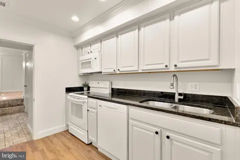 a kitchen with granite countertop white cabinets and a sink