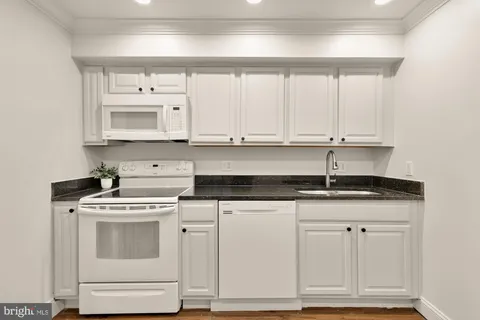 a kitchen with granite countertop white cabinets and sink