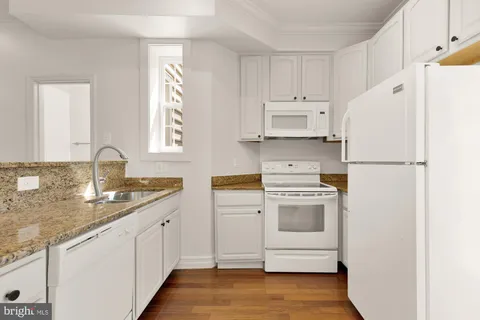 a kitchen with granite countertop white cabinets and white appliances