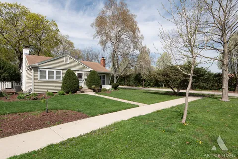 a view of house with a big yard and large trees