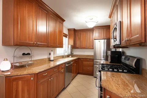 a kitchen with kitchen island granite countertop a sink stainless steel appliances and cabinets