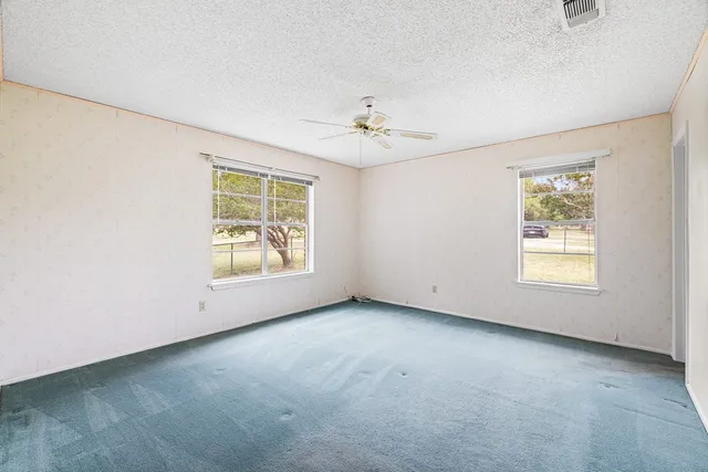 an empty room with a window and a ceiling fan