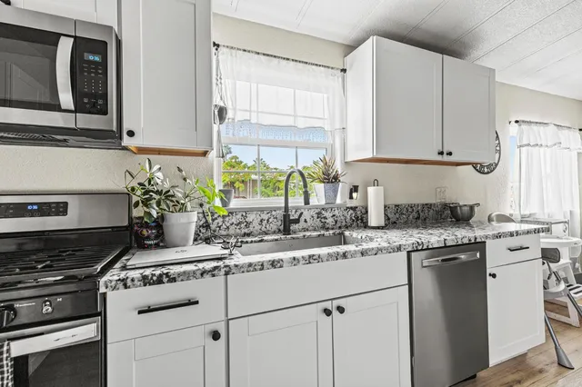 a large kitchen with stainless steel appliances granite countertop a lot of counter space and wooden floors
