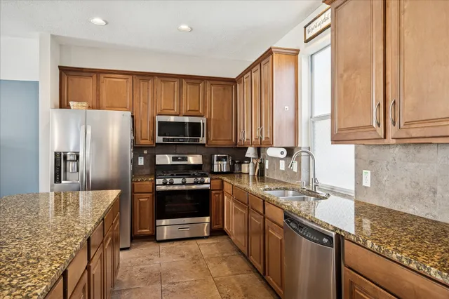 a kitchen with stainless steel appliances granite countertop a sink stove refrigerator and cabinets