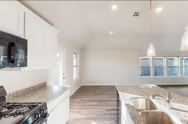 a kitchen with granite countertop a sink and a stove top oven