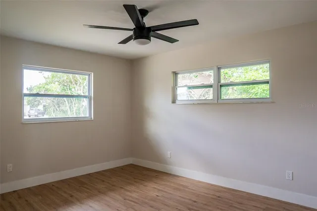 a view of empty room with wooden floor and fan