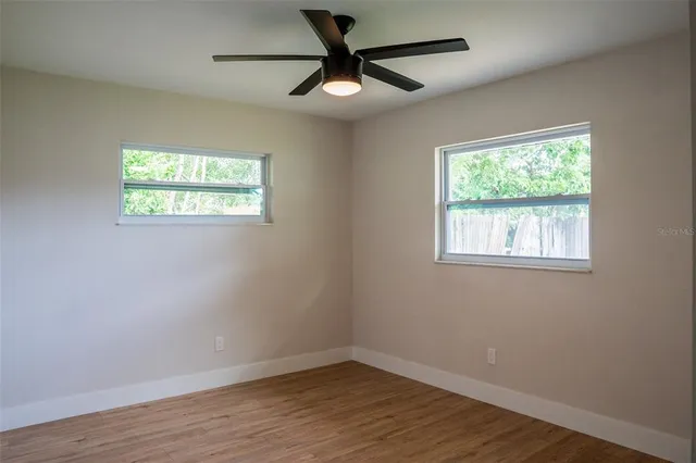 a view of an empty room with wooden floor and a window