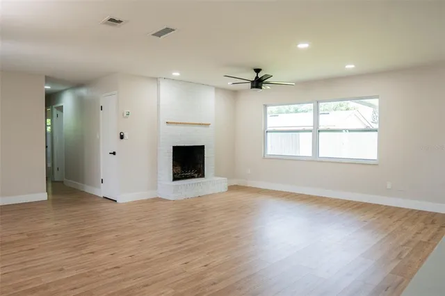 a view of an empty room with a window and wooden floor