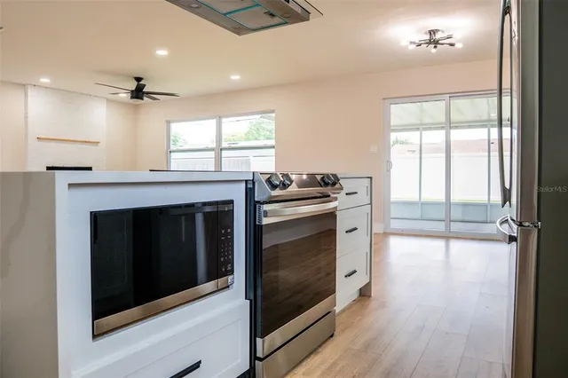 an empty room with wooden floor a ceiling fan and windows