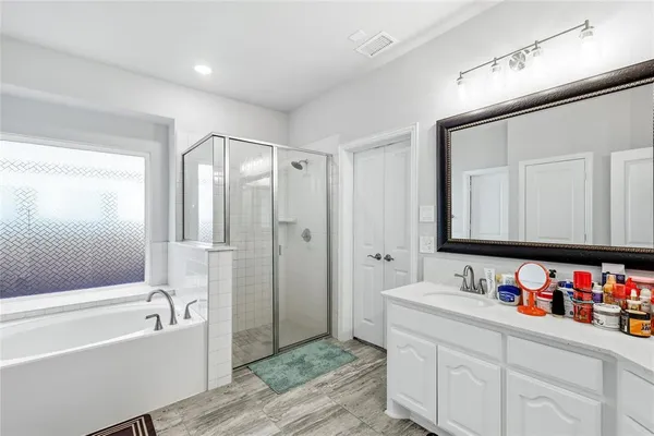 a bathroom with a tub sink double vanity and a mirror