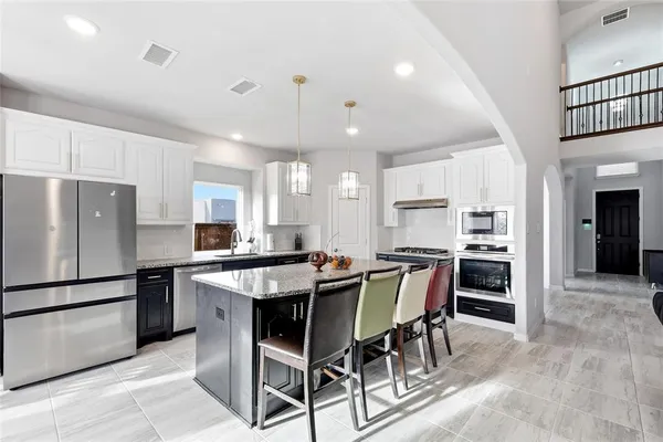 a kitchen with kitchen island a dining table wooden floor cabinets and appliances