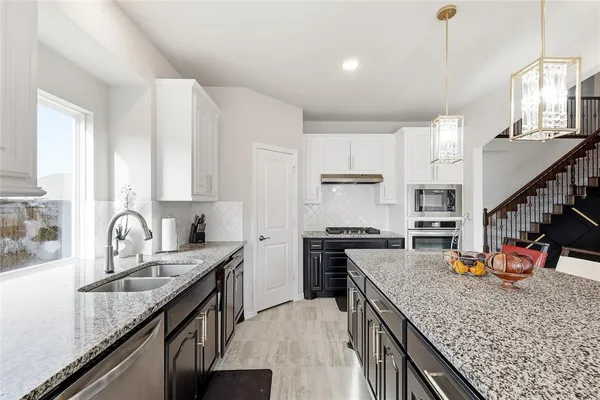 a kitchen with stainless steel appliances granite countertop a sink stove and cabinets