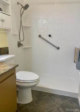 a bathroom with a granite countertop sink and a toilet