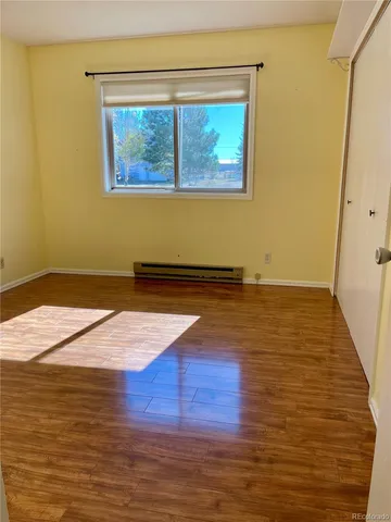 a view of empty room with window and wooden floor