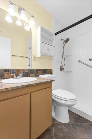 a bathroom with a sink a toilet a mirror and shower